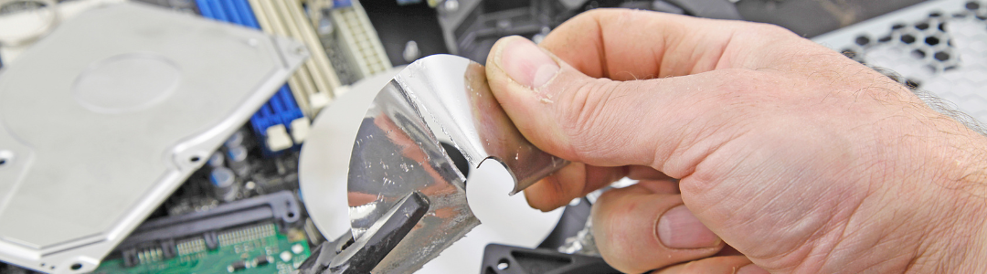 Integri.com.sg - Data Destruction Singapore A hand securely destroying a hard disk platter using pliers – representing physical data destruction in Singapore.